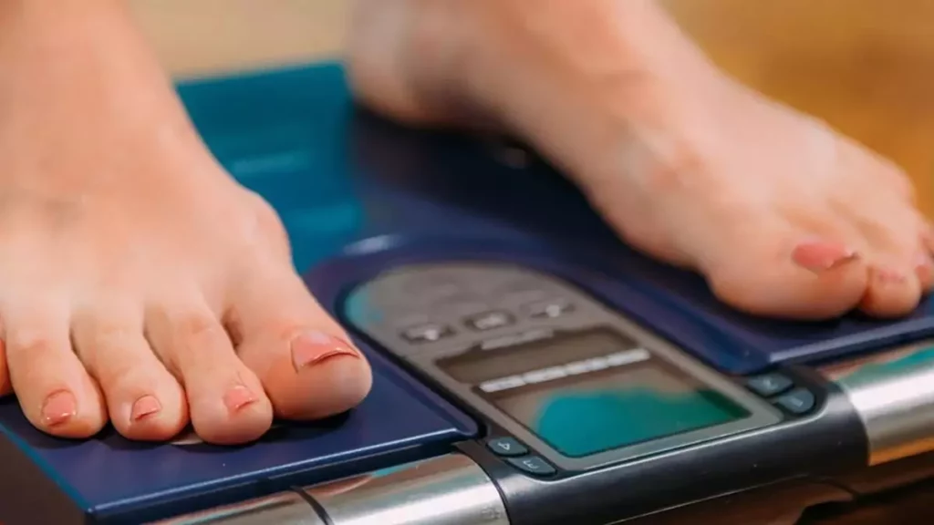 Pessoa checando parâmetros em balança de bioimpedância