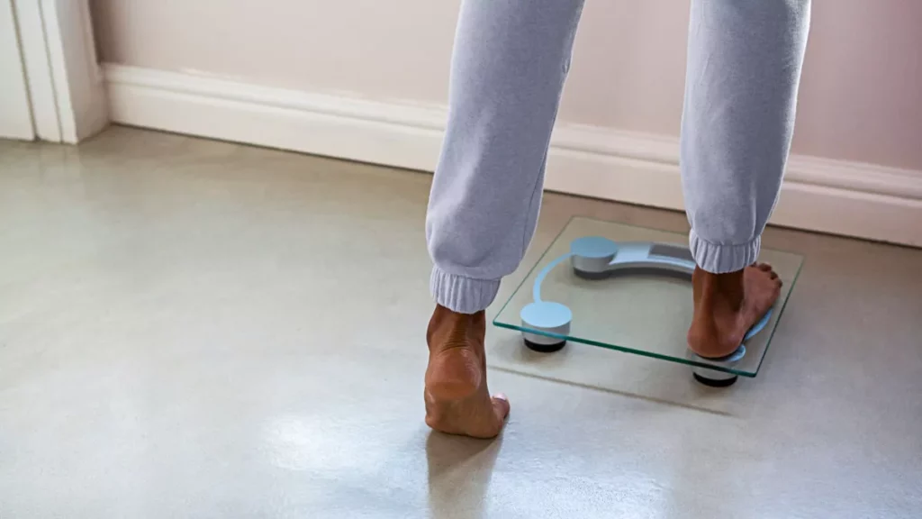 Pessoa se pesando em balança digital